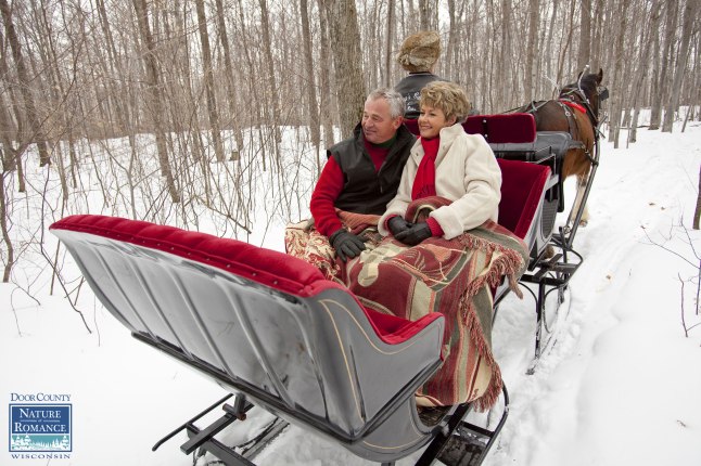A couple enjoys a romantic horse-drawn sleigh ride through the woods in Door County, Wisconsin during the annual Nature of Romance promotion. Photo courtesy Mike Roemer/DoorCounty.com.